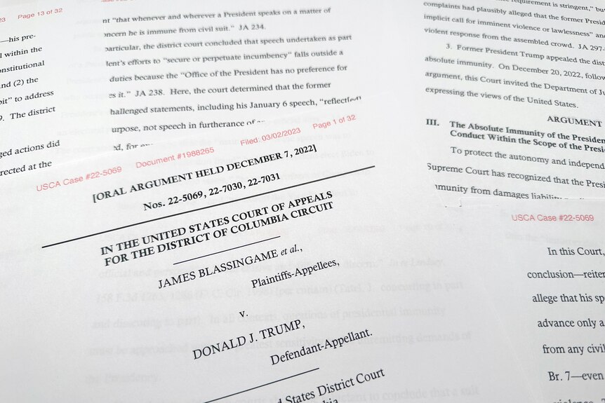 A close-up view of a stack of papers shows a lawsuit filed against former US president Donald Trump.
