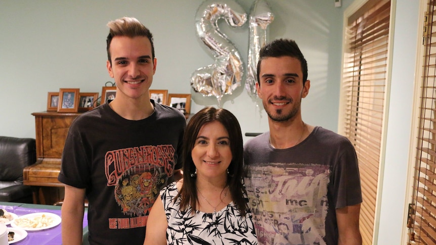 A woman with brown straight hair stands between her two sons, in a story about how to choose paint colour.