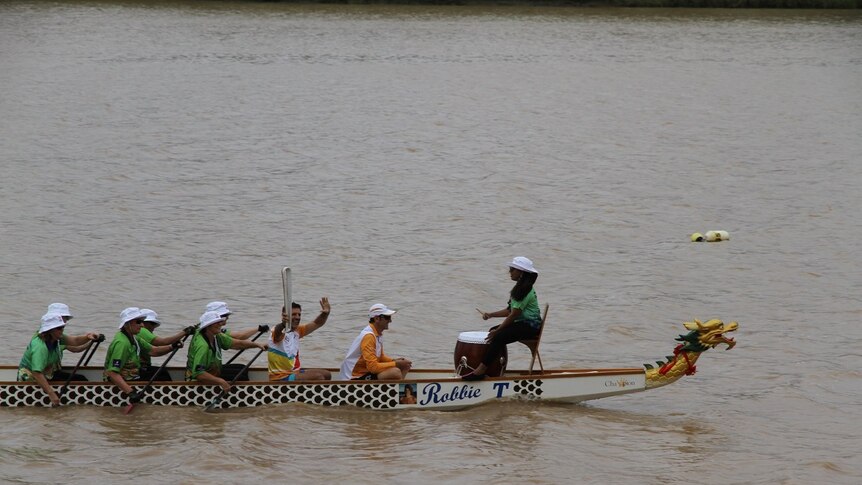 The Commonwealth Games Queen's Baton held by a man in a dragon boat in the Fitzroy River in Rockhampton