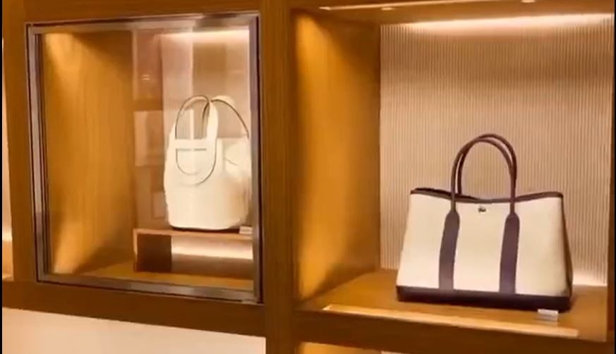 A screen grab shows an image of two high end beige handbags set in expensive timber shelving.
