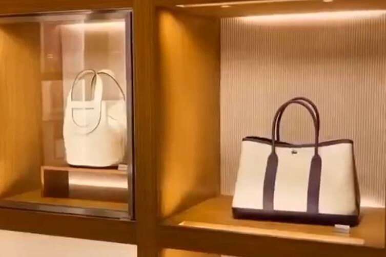 A screen grab shows an image of two high end beige handbags set in expensive timber shelving.