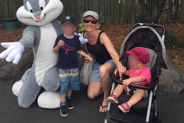 A woman in shorts and sunglass with two small children and another person in a rabbit costume