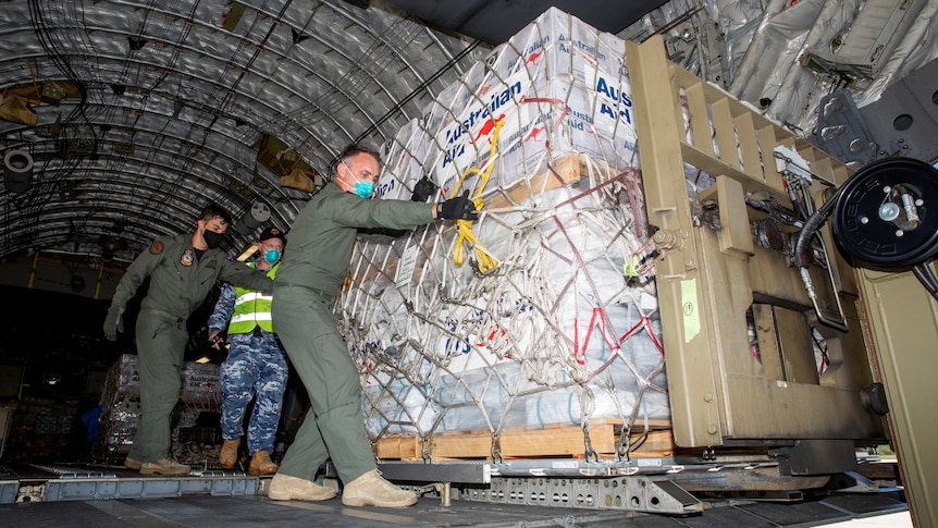 Australian Defence Forces members unload humanitarian assistance and engineering equipment from an aircraft.