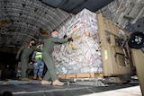 Australian Defence Forces members unload humanitarian assistance and engineering equipment from an aircraft.