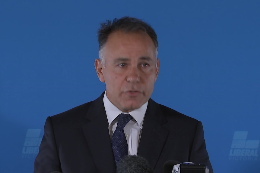 John Pesutto standing in front of a blue backdrop.