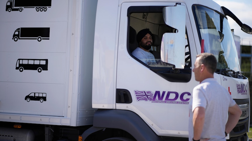 An instructor watches as a learner truck driver practises reversing