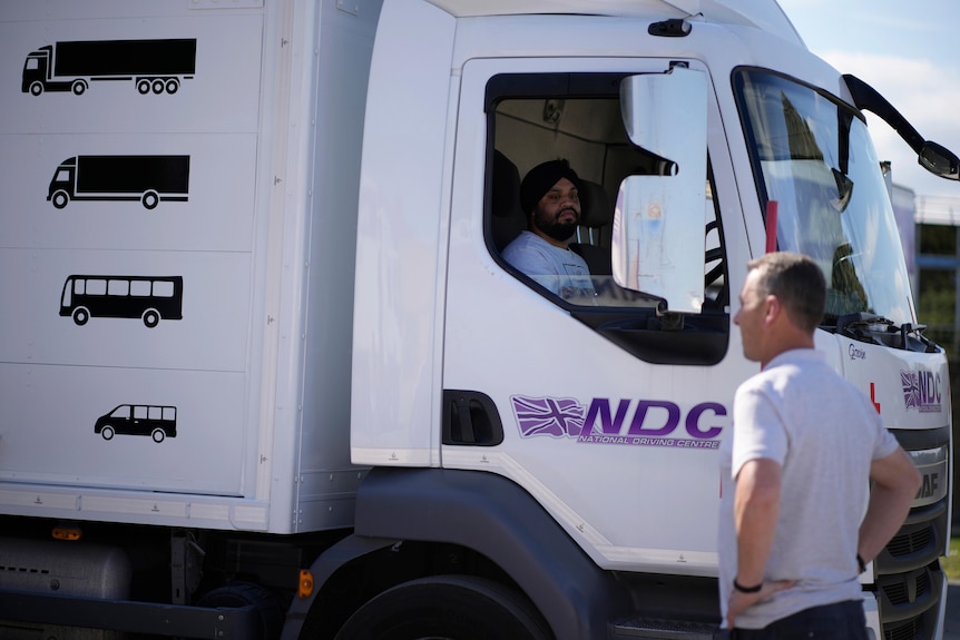 An instructor watches as a learner truck driver practices reversing