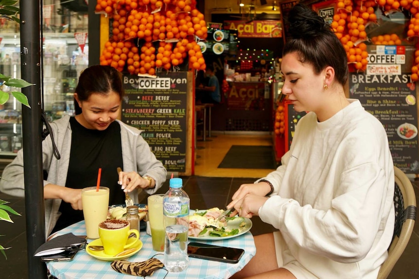 Two women dine at an outdoor table in Melbourne's CBD.