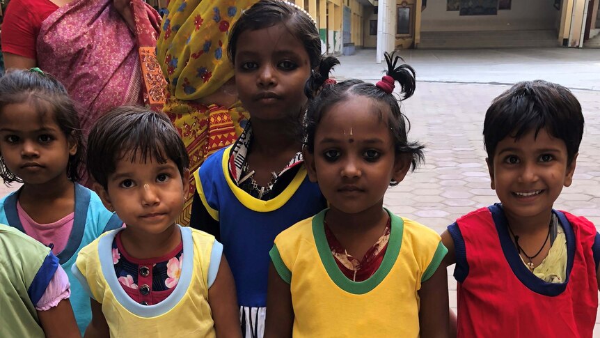Five smiling girls in brightly coloured dresses at a school in India