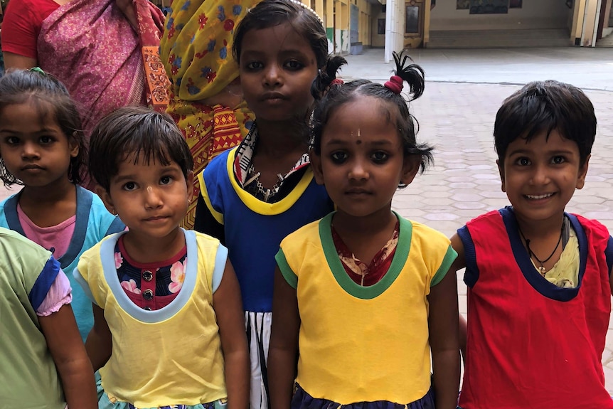 Five smiling girls in brightly coloured dresses at a school in India