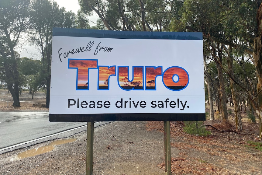 A white sign saying "Farewell from Truro" on the side of a wet road.