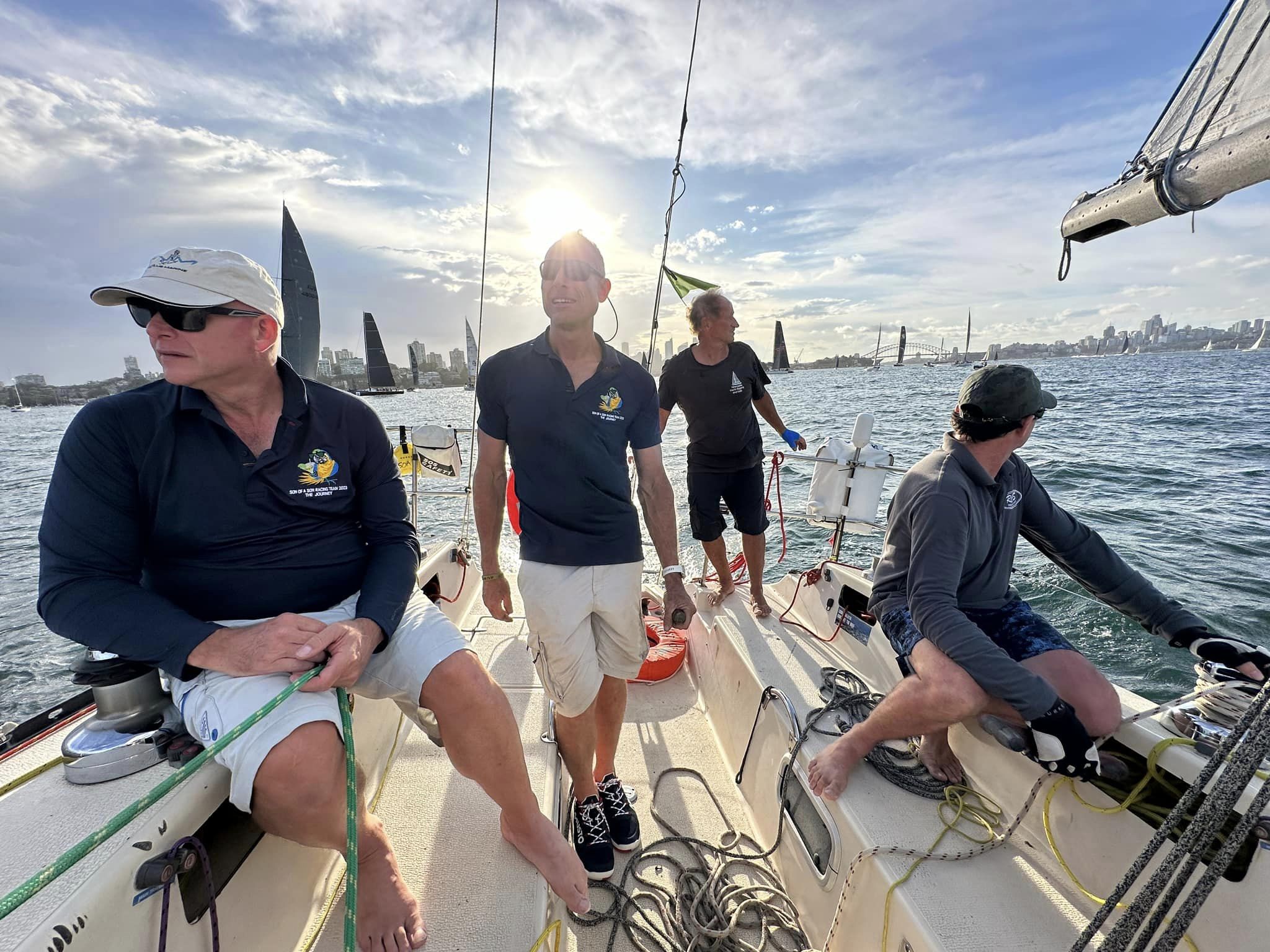Sailors on the deck of a yacht with sun behind. 