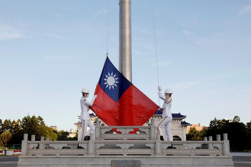 Two soldiers raise Taiwan flag.