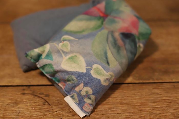A floral wheat bag on a wooden table.