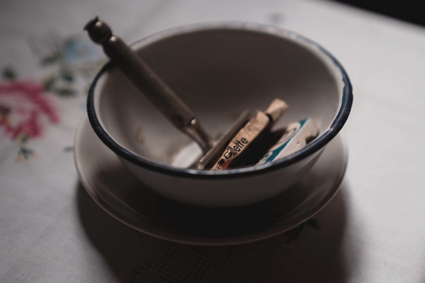 Old medical instruments in a metal bowl.