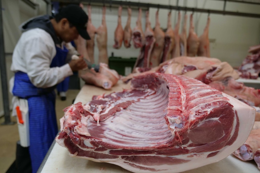 A pork middle sits on a butchershop bench