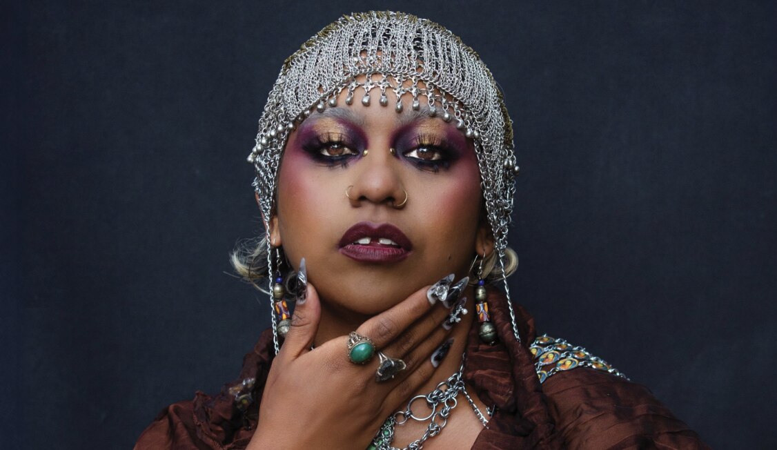 Una mujer que lleva un tocado adornado y maquillaje de ojos pesados