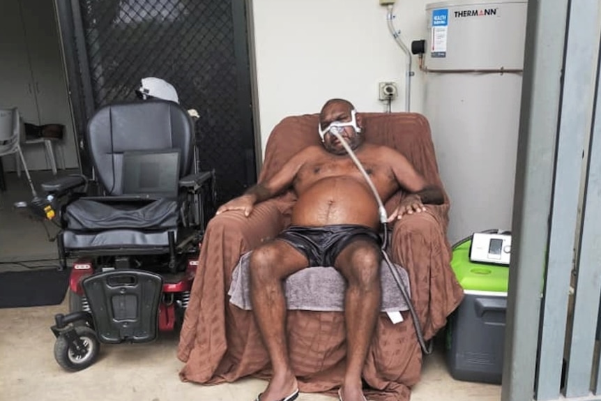 man sits in wheelchair with respirator attached