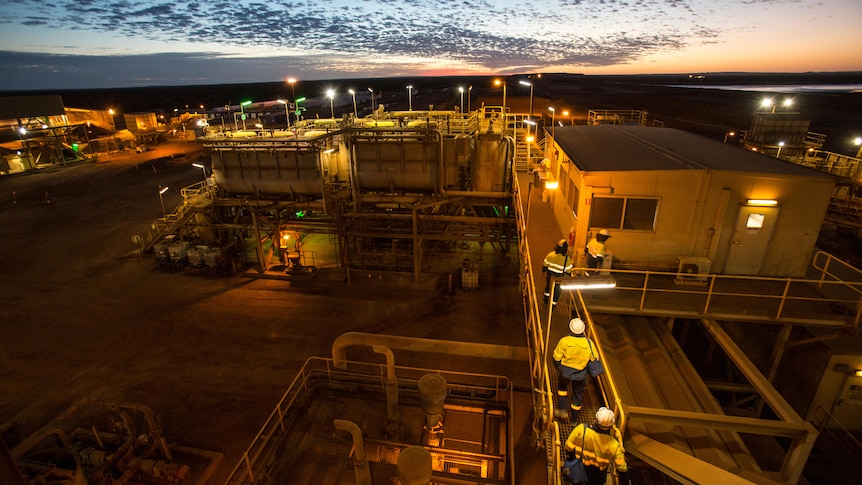 Workers walking next to dongas at sunset.