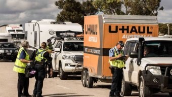 Police check vehicles at a road block.