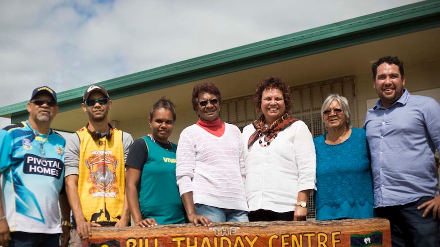 Seven members of the Thaiday family stand in row with 'Bill Thaiday Centre' in foreground