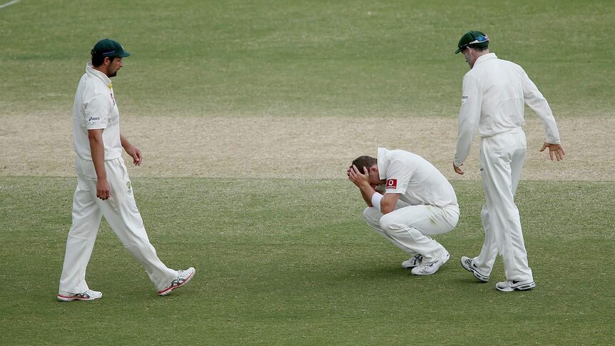 Peter Siddle (centre) sinks to his knees while team-mates Mike Hussey (right) and Ben Hilfenhaus walk over to console him