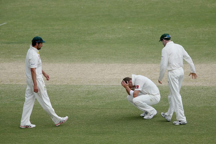 Peter Siddle (centre) sinks to his knees while team-mates Mike Hussey (right) and Ben Hilfenhaus walk over to console him