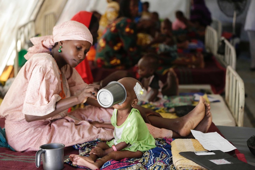 A mother feeds her malnourished child at a feeding centre.