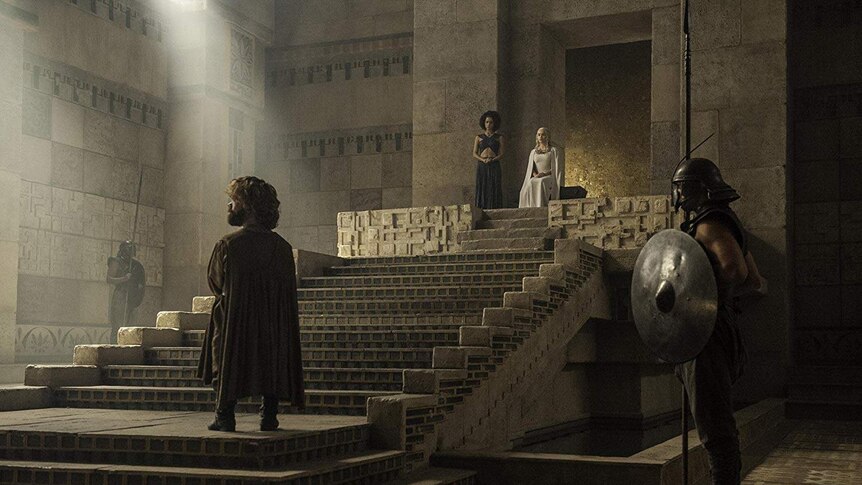 Peter Dinklage, Nathalie Emmanuel, and Emilia Clarke in front of stairs and a throne in the HBO series Game of Thrones