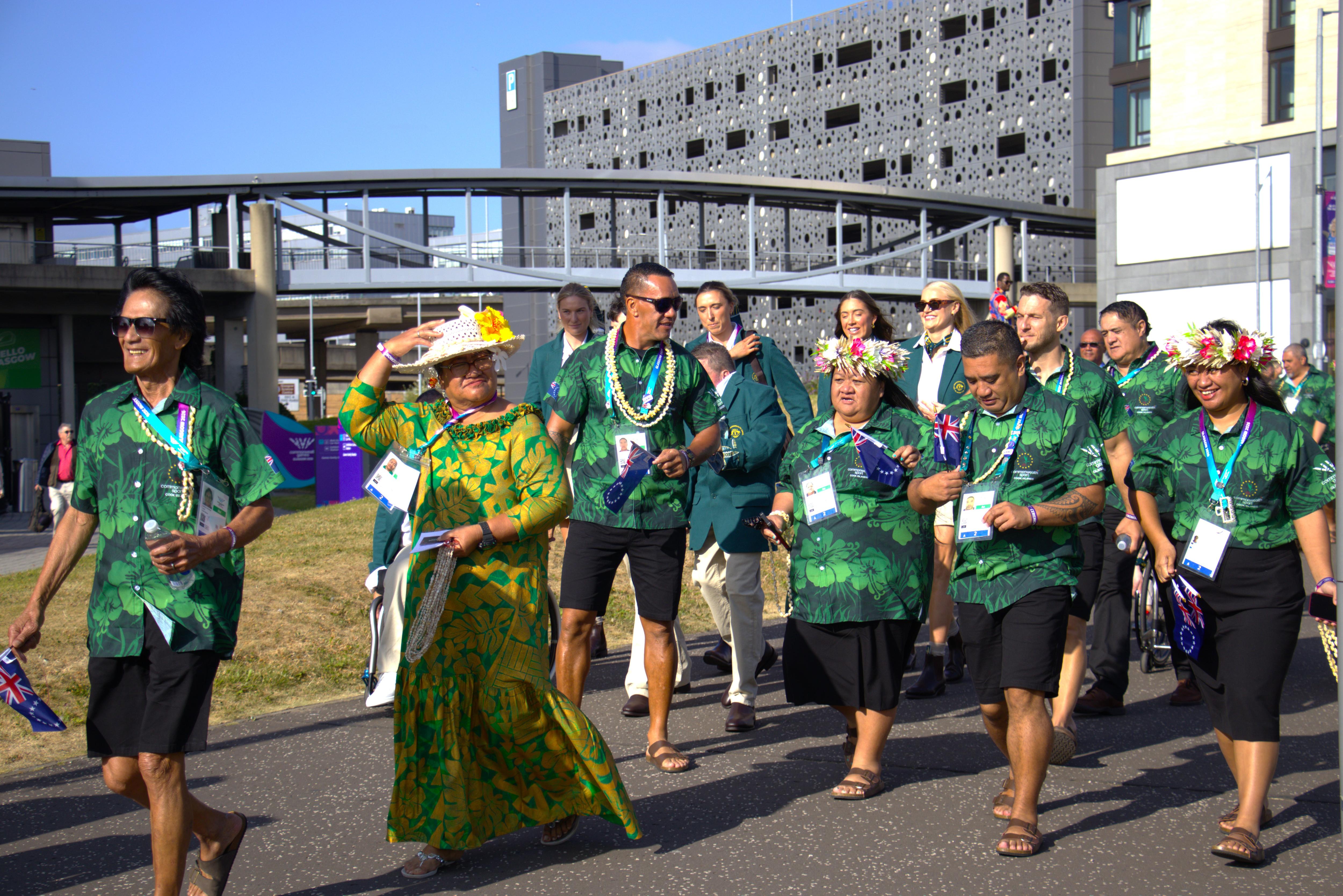 A group of people wearing Cook Islands colours walk along a path.