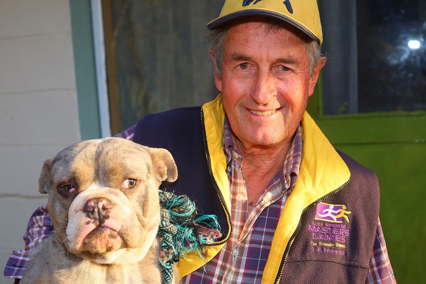 man wearing cap and jacked holding dog