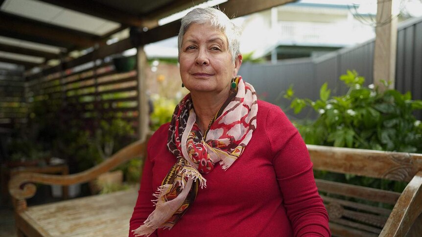 A woman stands undercover outside her home.