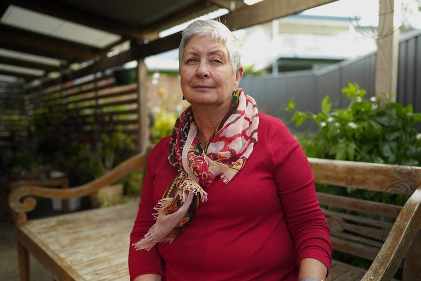 A woman stands undercover outside her home.