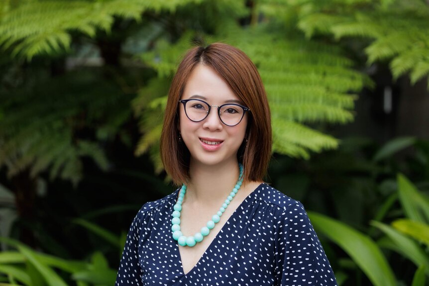 A portrait of Dr Carys Chan, a lecturer at Griffith University. She's smiling while standing in front of a lush garden.