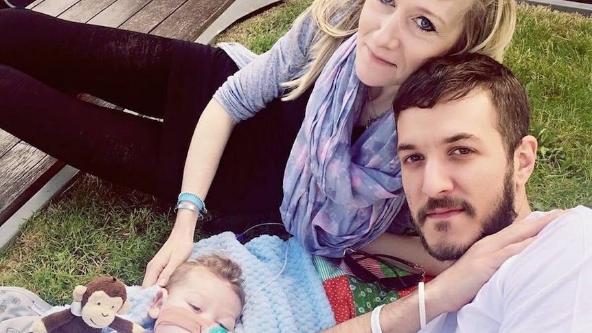 Terminally ill baby Charlie Gard with his parents, Connie Yates and Chris Gard, lying on the ground.