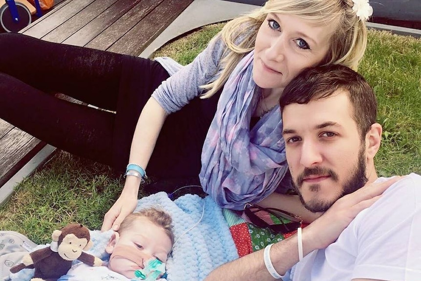 Terminally ill baby Charlie Gard with his parents, Connie Yates and Chris Gard, lying on the ground.