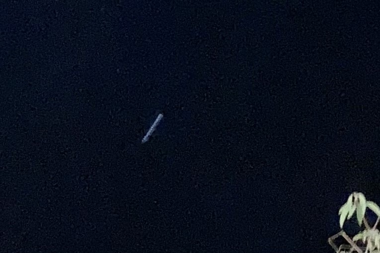 A grey cylindrical object pictured in the night sky 