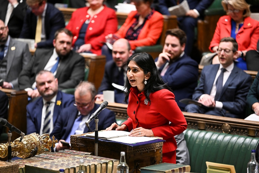 Braverman, wearing a bright red jacket, leans forward as she speaks at a lectern in the house of commons
