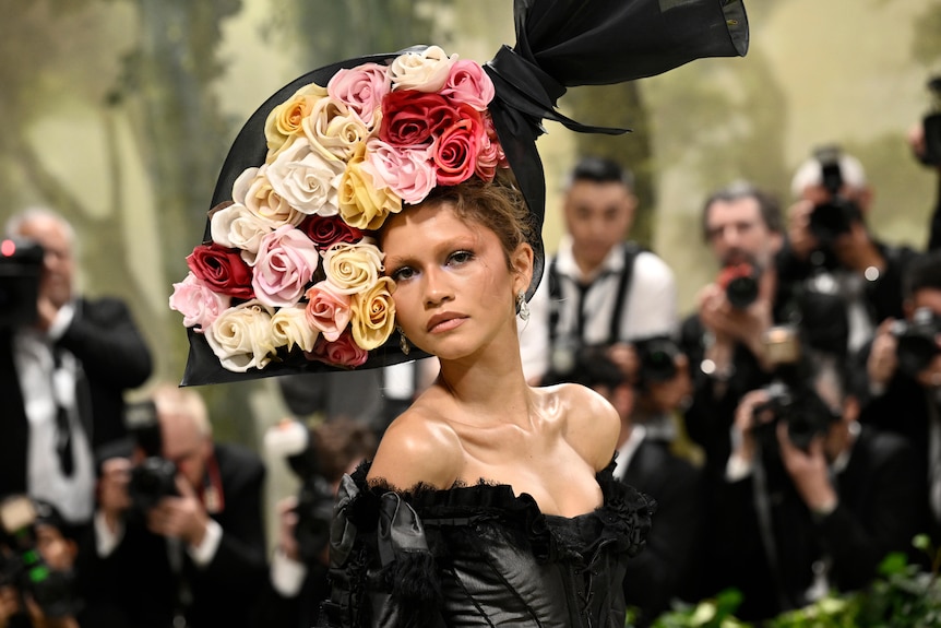A close up of Zendaya wearing a black corset with a headpiece that looks like a bouquet of roses