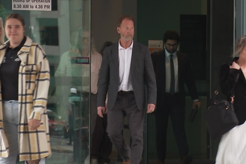 a man in a suit walks out of a brisbane courthouse