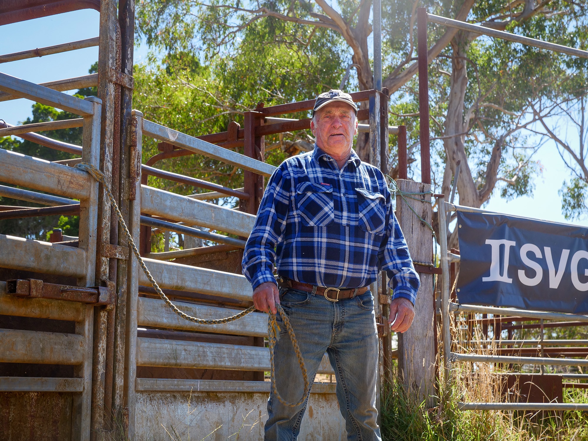 A man stands in the middle of a rodeo ring holding a rope