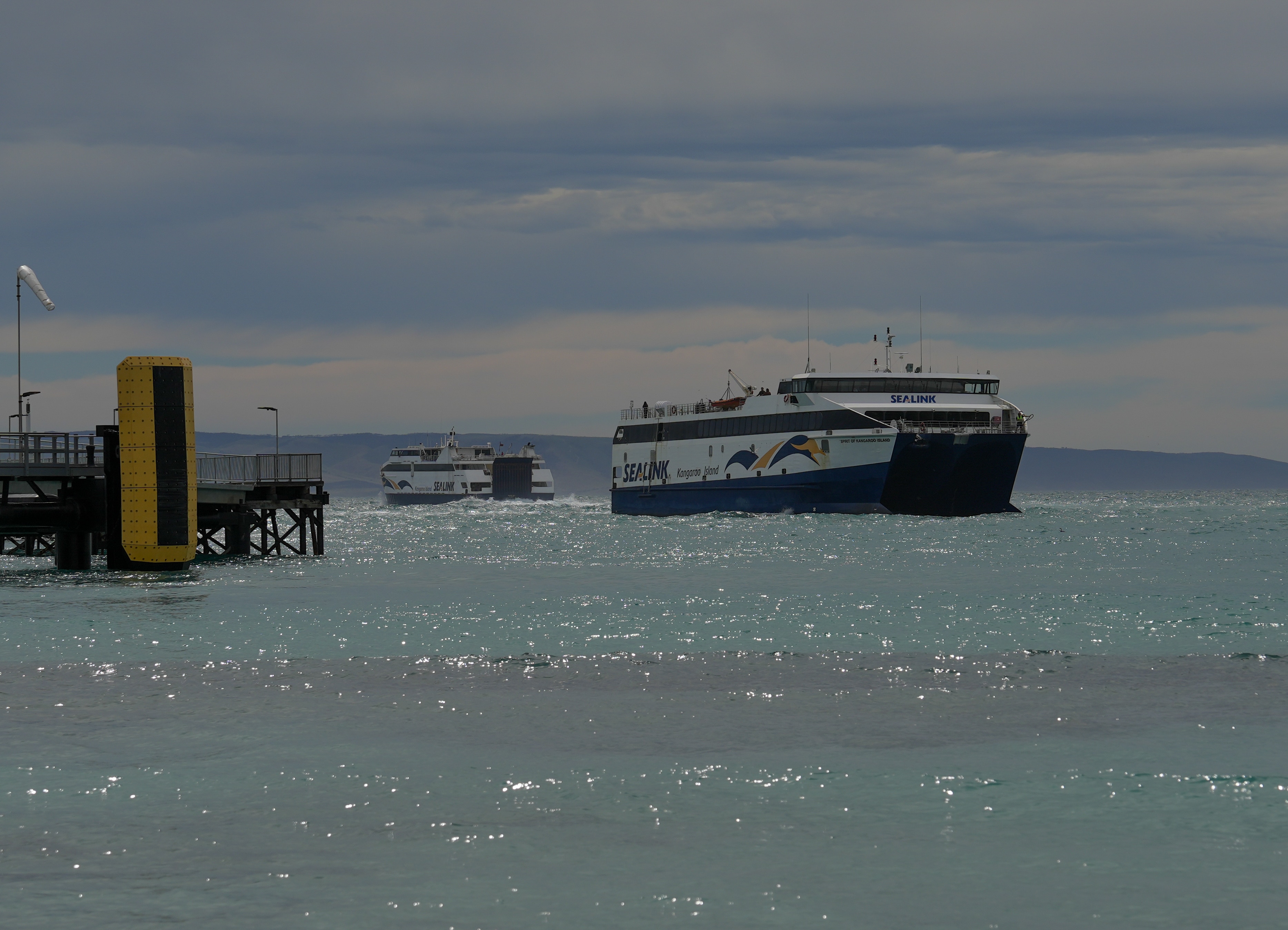 Two ferries which have SeaLink logos are on the water in the distance.