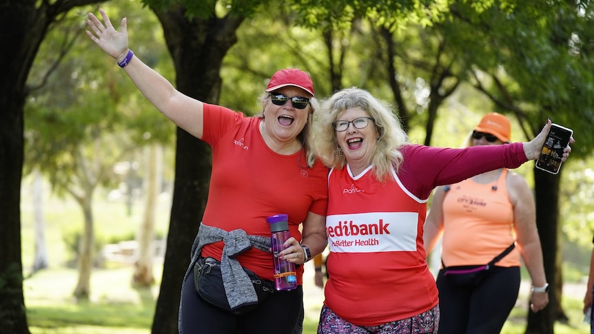 Suzanna Crane and a friend smile and hold their arms out wide.