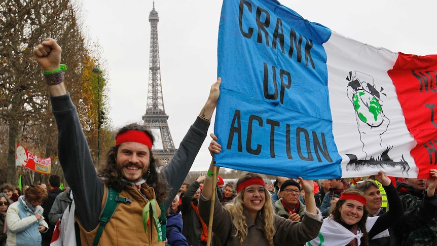 Climate change protesters in Paris hold a banner which reads "Crank up the Action"