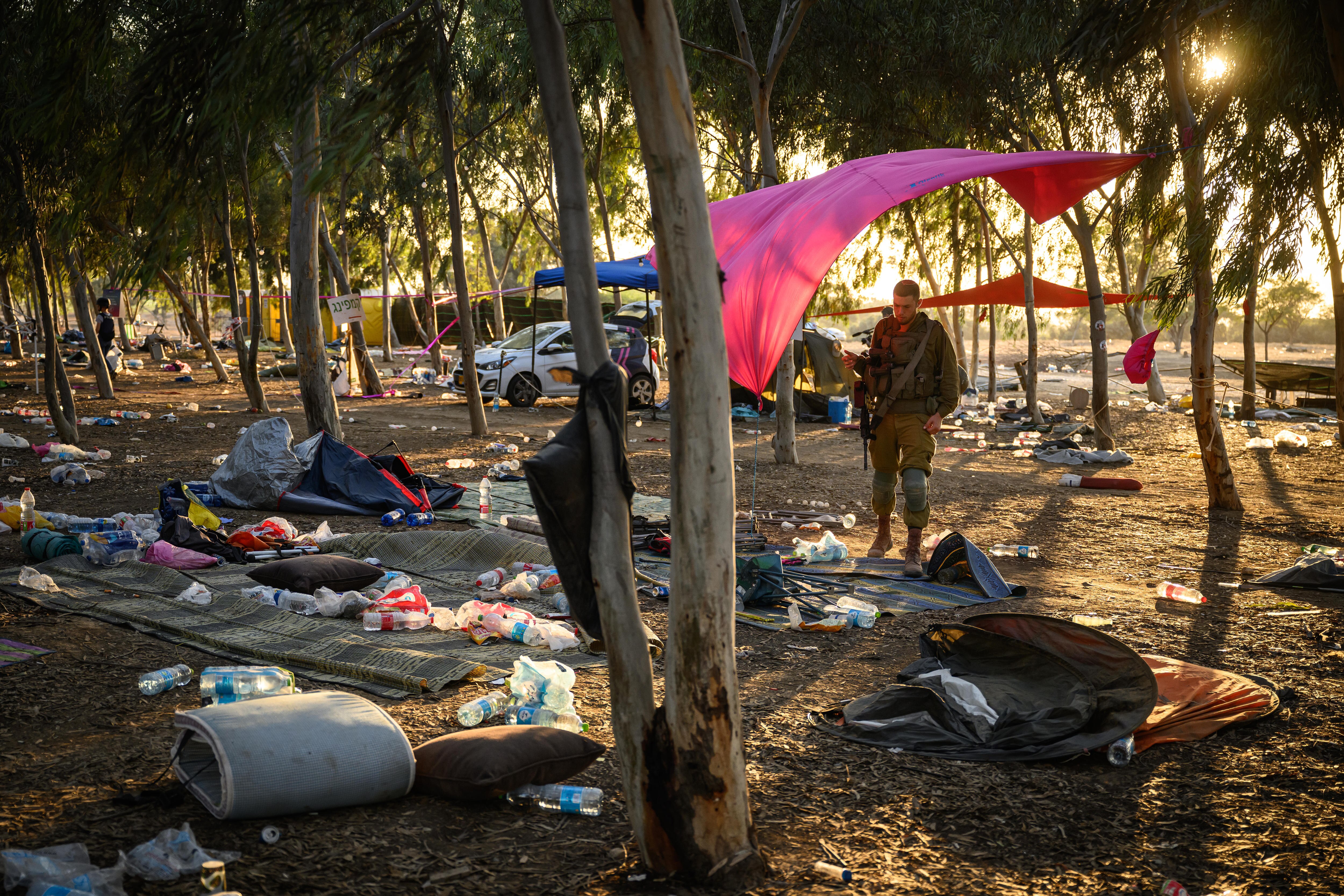 A soldier stands looking down at the scattered camping gear 