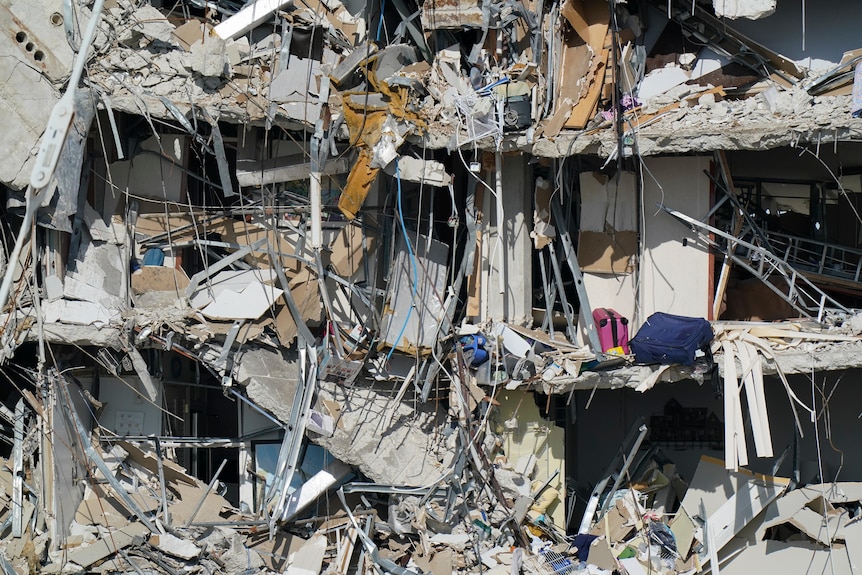 Personal belongings are seen amid debris dangling from the remains of apartments in Miami