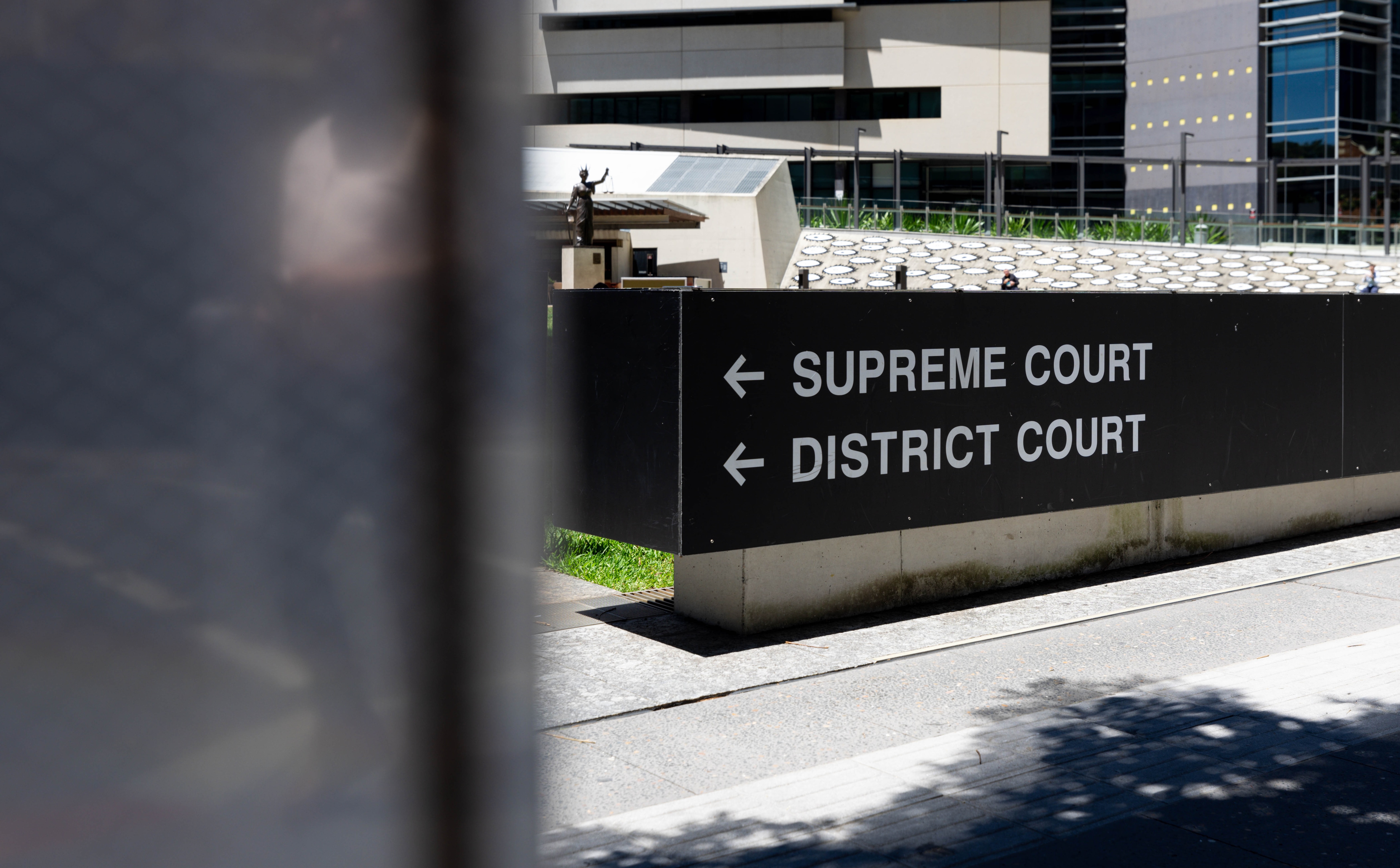 A black sign showing Brisbane's Supreme and District Court