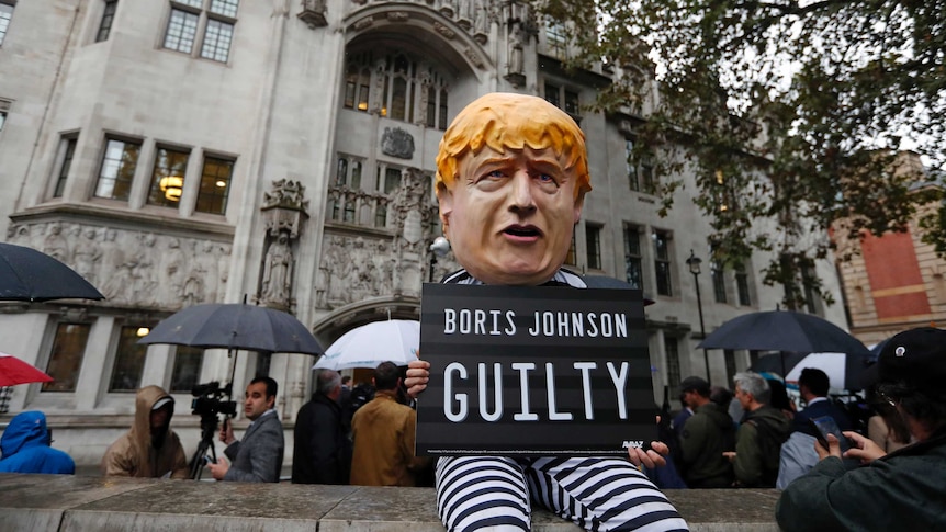 A man dressed up as Boris Johnson stands outside the Supreme Court. He wears a black and white stripe prison outfit.