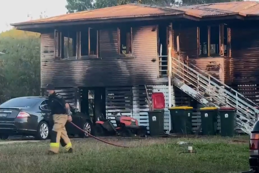 Firefighter outside burnt house 