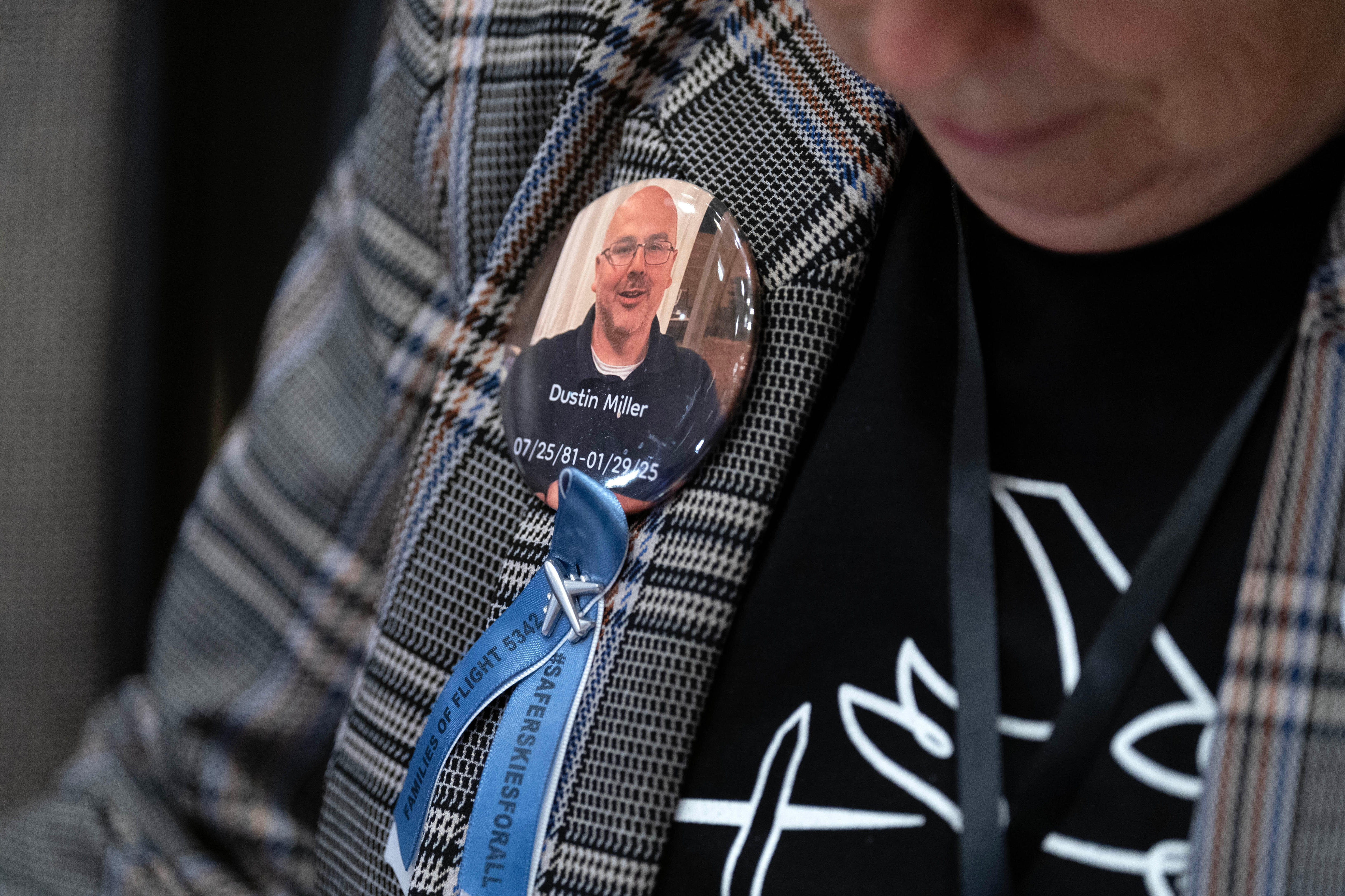 Un primer plano de un alfiler de un hombre calvo con gafas en la solapa de una chaqueta de mujer.